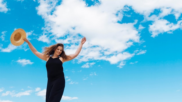 Free photo low angle of woman enjoying a beautiful day out with sky and clouds