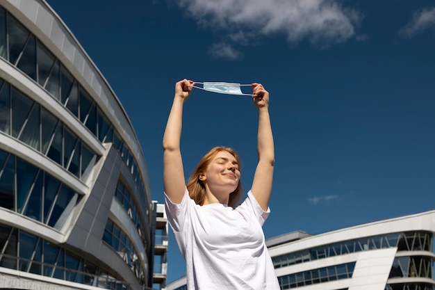 Low angle woman holding mask