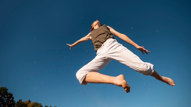 Low angle woman jumping in nature