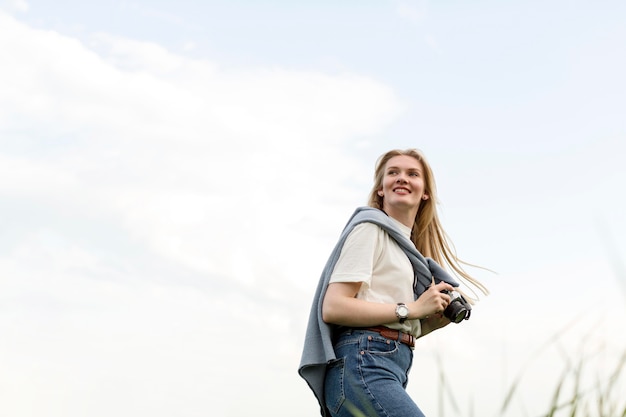 Free Photo low angle of woman posing while holding camera