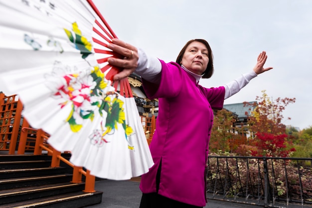 Free photo low angle woman practicing tai chi outside