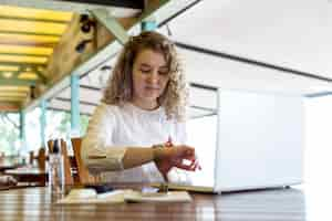 Free photo low angle woman at terrace working on laptop