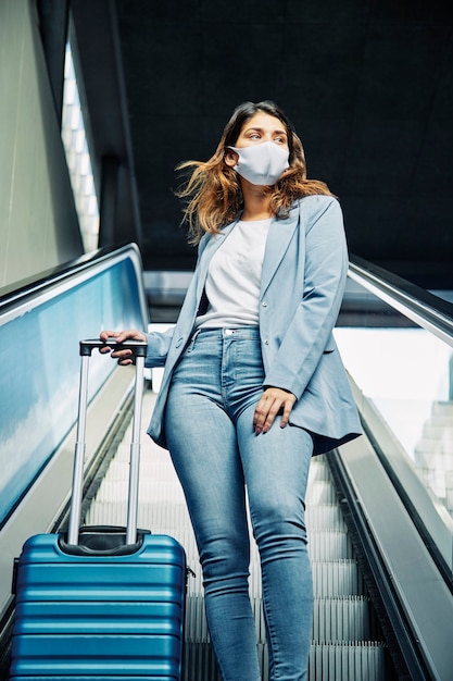 Low angle of woman with medical mask on escalators during the pandemic