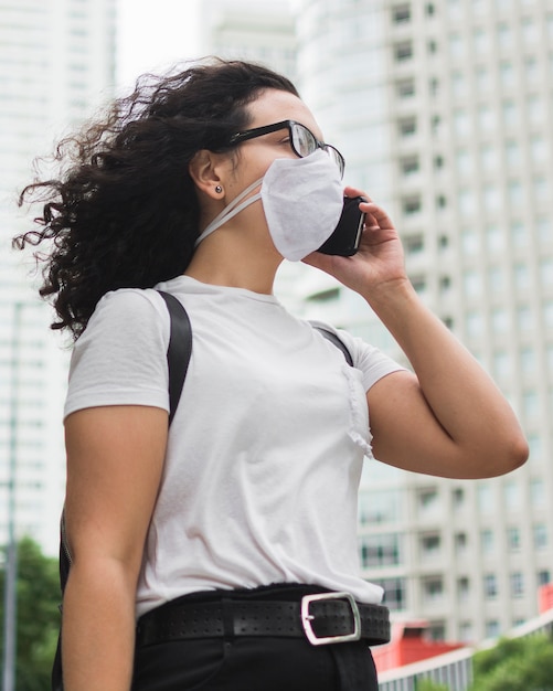 Free Photo low angle woman with medical mask talking on the phone