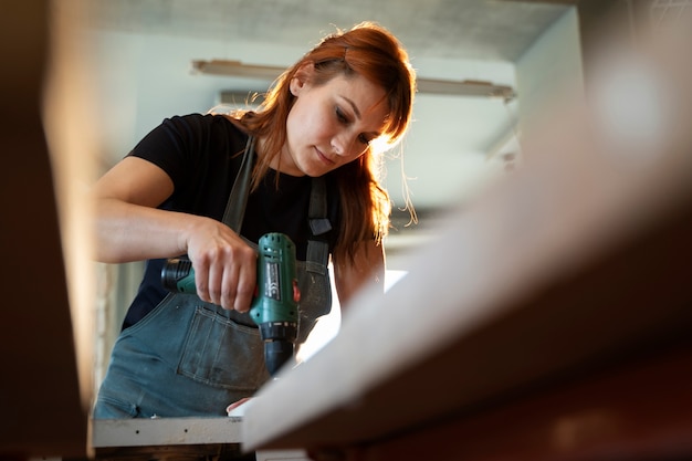 Free photo low angle woman working with drill