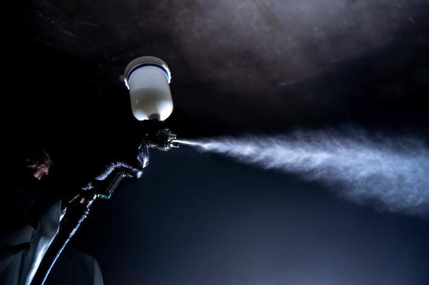 Free photo low angle worker spraying powder paint from a gun