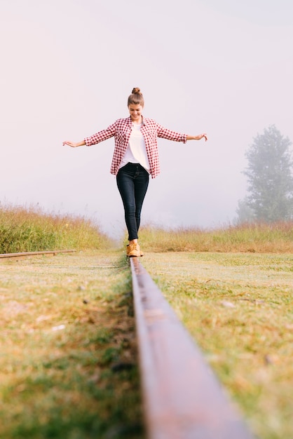 Free photo low angle young girl balancing on railway