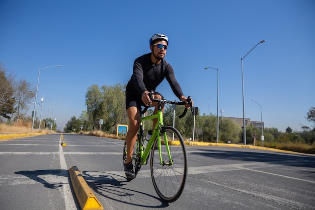 Free photo low anglhispanic man in a sports suit riding a bicycle in a city