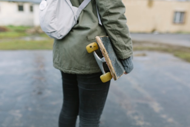 Low section of female skater standing with skateboard