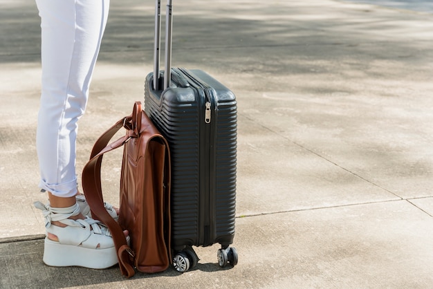 Free photo low section of female tourist standing on road with luggage and leather bag