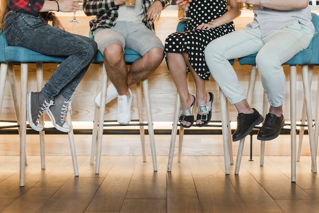 Free photo low section of friends sitting on bar stool