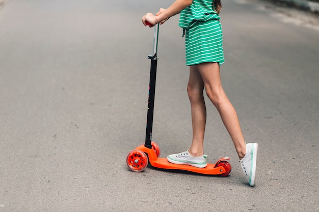 Free photo low section of a girl riding push scooter on street