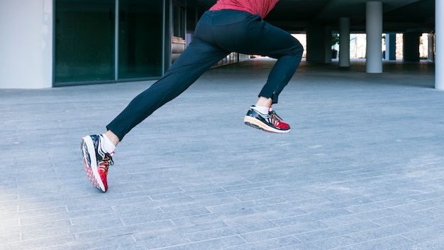 Free photo low section of male athlete running and jumping at outdoors