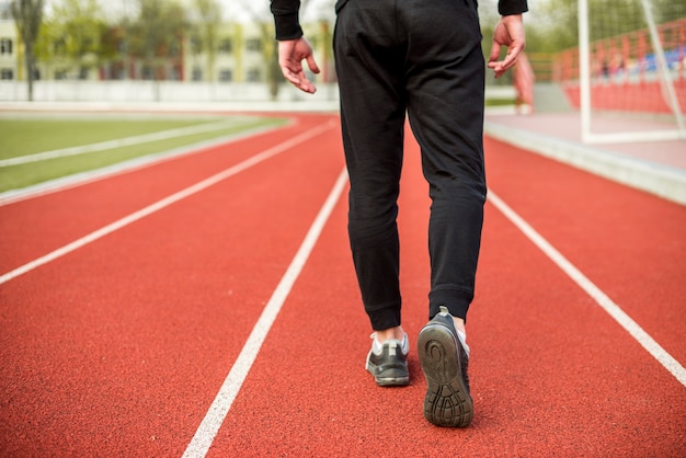 Free photo low section of a male athlete walking on red race track