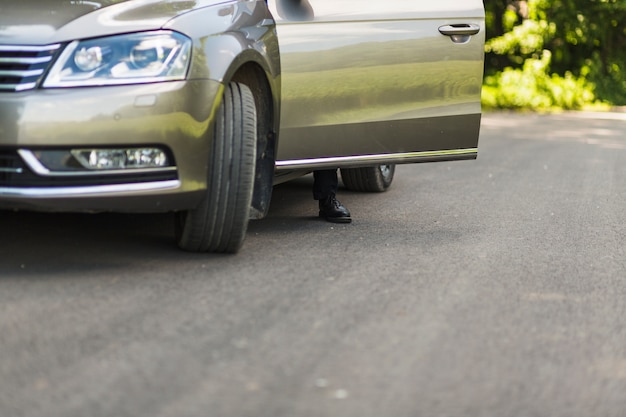 Low section of a man's foot behind car's open door