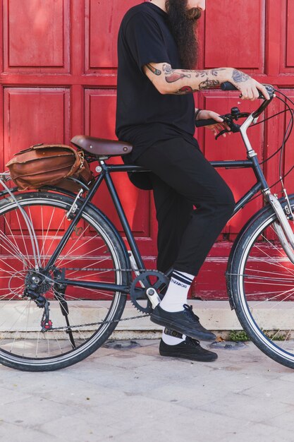 Low section of a man sitting with bicycle in front of door