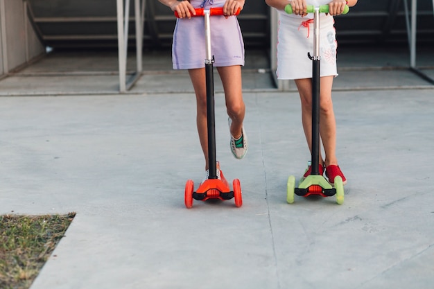 Free photo low section of two girls standing on their kick scooter