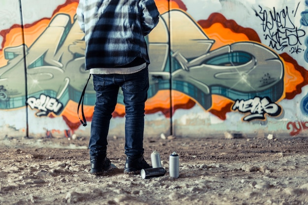 Free photo low section view of artist standing near spray can in front of graffiti on wall