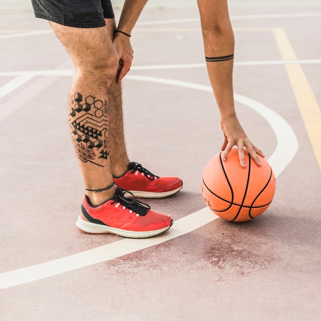 Free photo low section view of a man picking up basketball in court