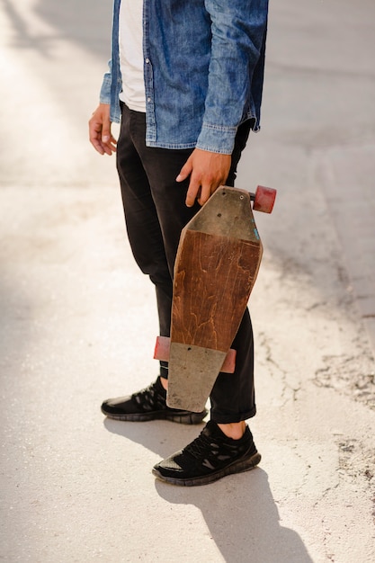 Free photo low section view of a man with wooden skateboard