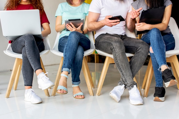 Low section view of people sitting on chair using wireless devices