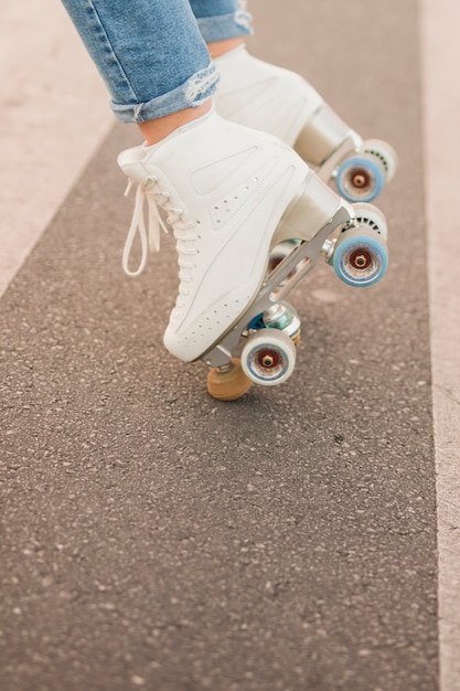 Low section of woman's foot wearing white roller skate balancing on road