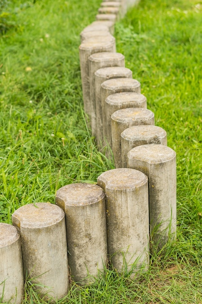 Low stone pole barrier on green grass in soft focus