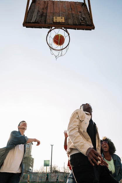 Free photo low view group of friends playing basketball outdoors