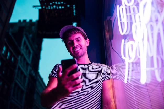 Low view of man looking at his phone and smile