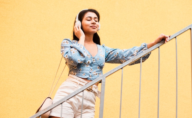 Free Photo low view woman holding her headphones