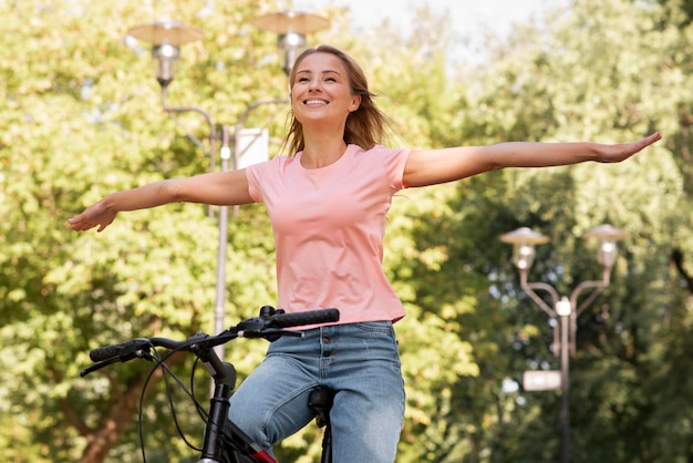 Free photo low view woman riding without holding the bike with hands