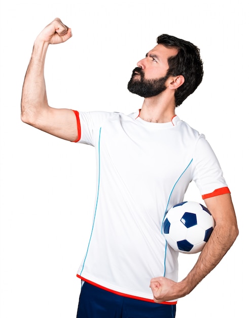 Free photo lucky football player holding a soccer ball