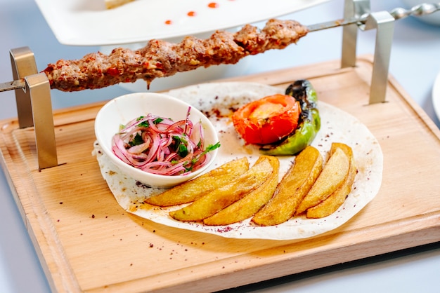 Lule kebab and fried potato with vegetables and onion