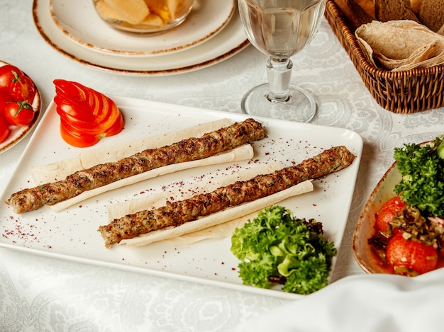 Free photo lule kebab on lavash and sliced tomato