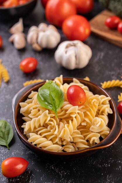 Macaroni sauteed with tomatoes and basil on a gray plate.