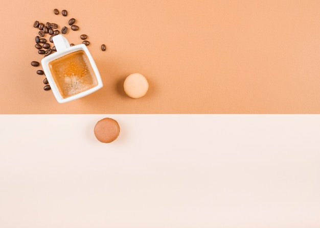 Free photo macaroons; coffee cup; and roasted coffee beans on dual background