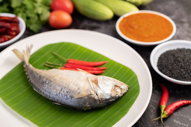 Mackerel placed on banana leaves on a white plate.