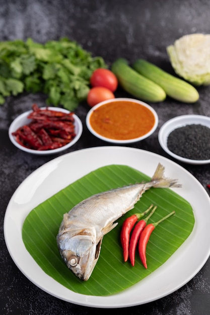 Mackerel placed on banana leaves on a white plate.