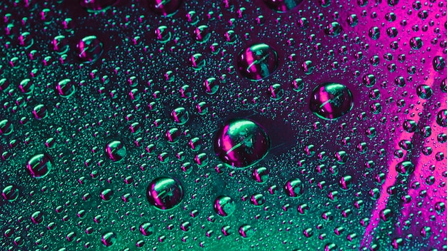 Macro of green and pink water drops on the surface