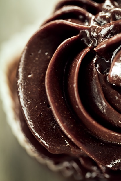 Macro of tasty beautiful appetizing chocolate homemade cupcake on wooden background. 