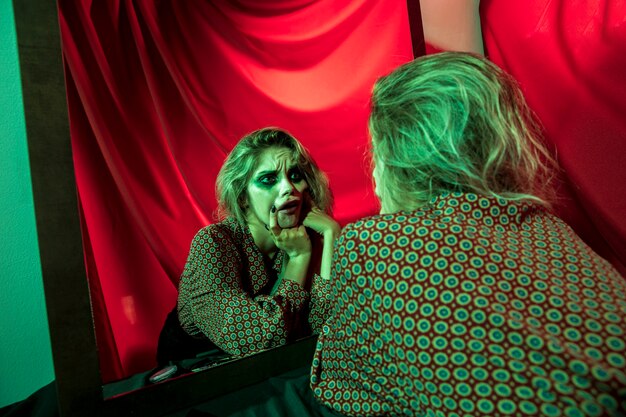 Mad halloween clown woman looking at herself