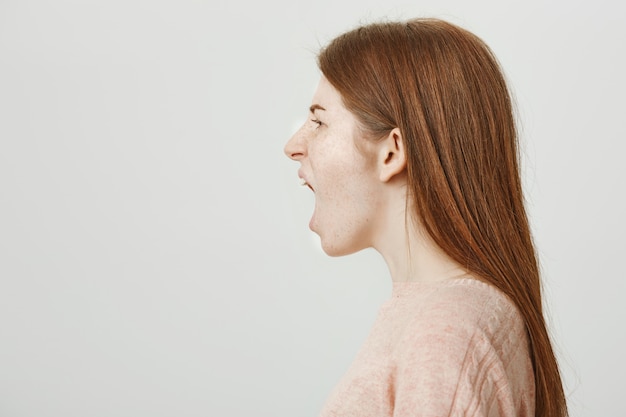 Free photo mad redhead woman standing profile and shouting angry