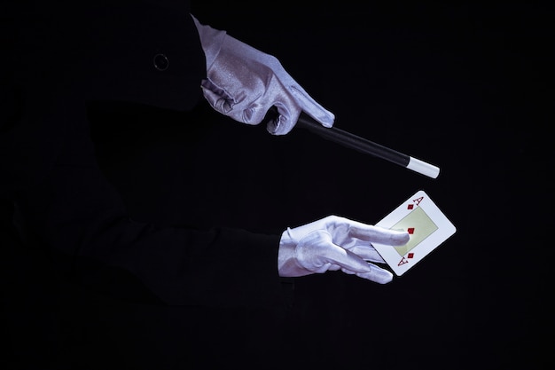 Free photo magician performing trick on aces playing card against black background