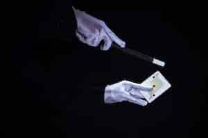 Free photo magician performing trick on aces playing card against black background