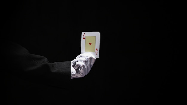 Free photo magician's hand holding aces playing card against black background