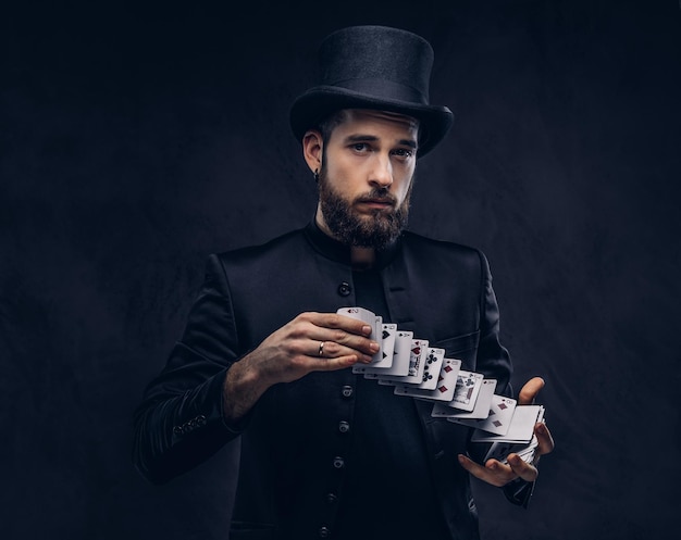 Free photo magician showing trick with playing cards on a dark background.