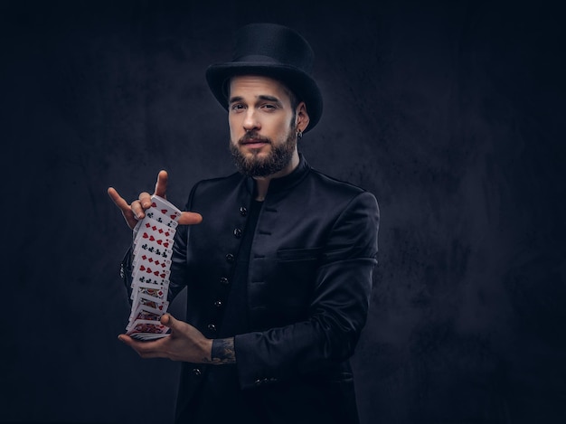 Free Photo magician showing trick with playing cards on a dark background.