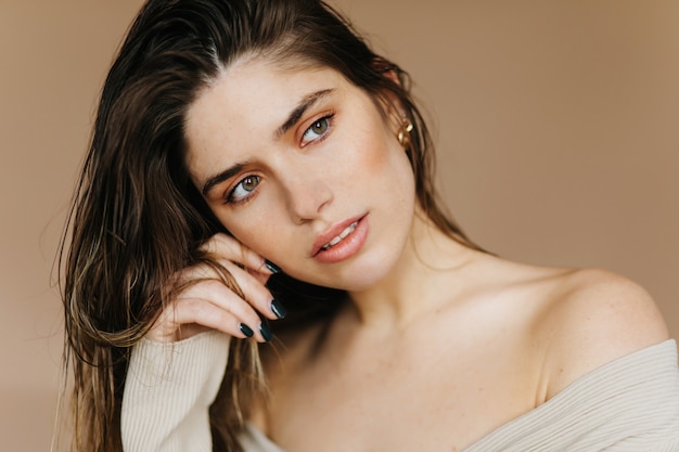 Magnificent young woman with light makeup. Pensive attractive girl posing on brown wall.