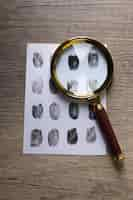 Free photo magnifying glass with envelope with fingerprints on wooden background