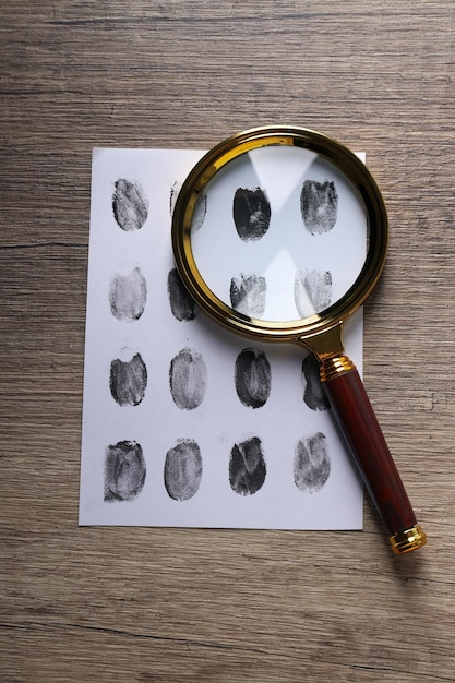 Free Photo magnifying glass with envelope with fingerprints on wooden background